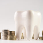 A white tooth next to piles of coins for a blog post about how to afford dental care without insurance