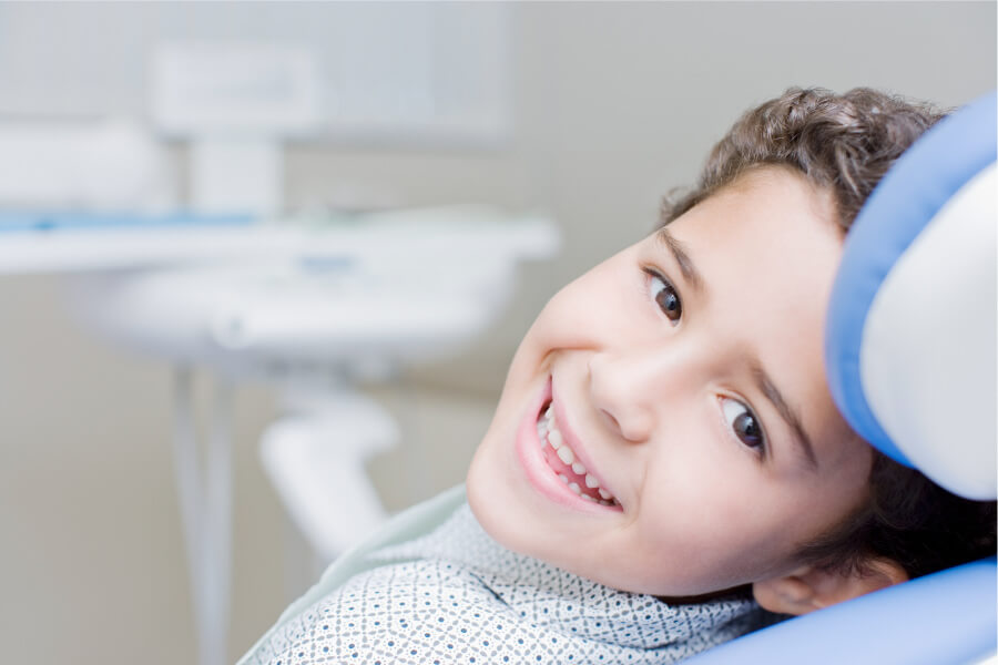 Brunette boy smiles while sitting in the dental chair at a regular dentist or family dentist in Summerville, SC