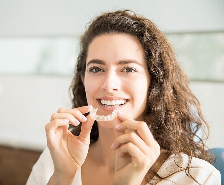 woman inserting her clear aligners on her teeth